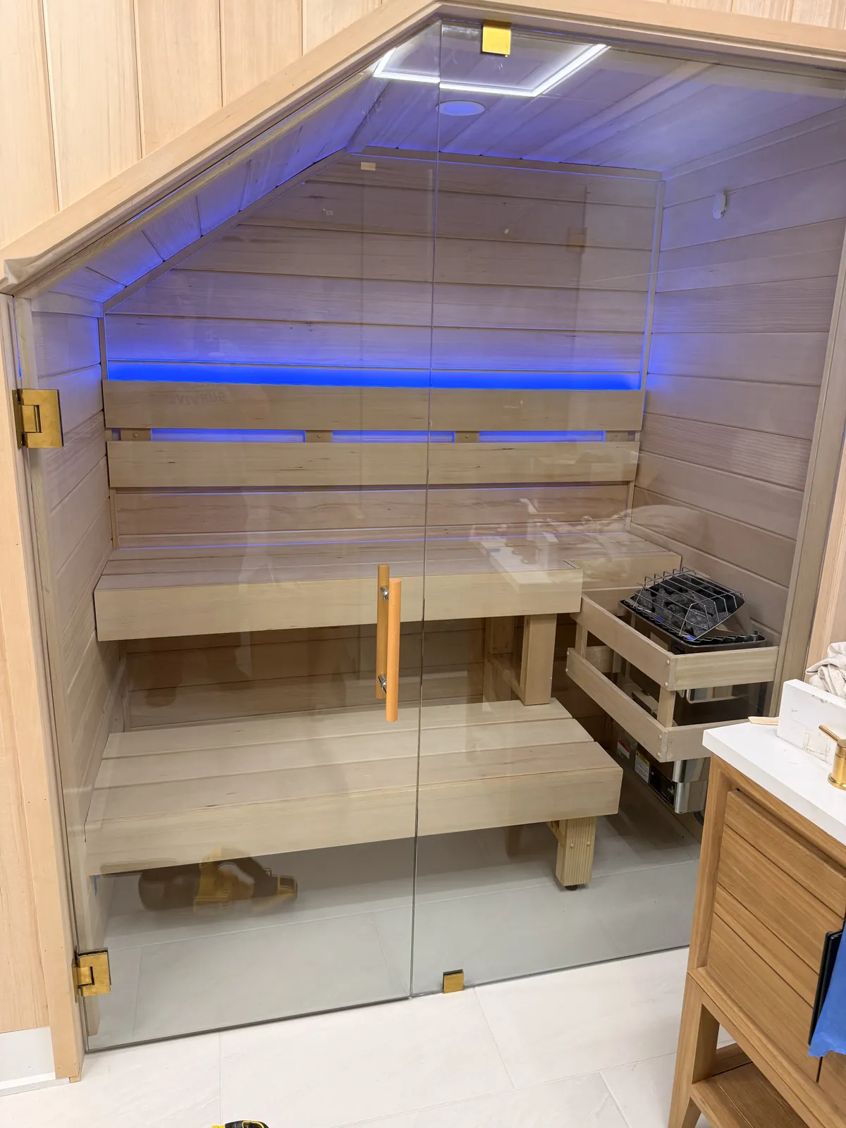Glass-front custom sauna with blue LED lighting